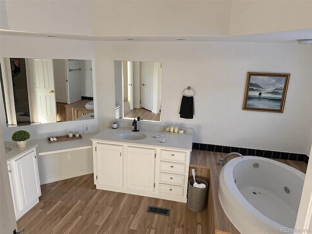 bathroom featuring hardwood / wood-style flooring, vanity, and a bath