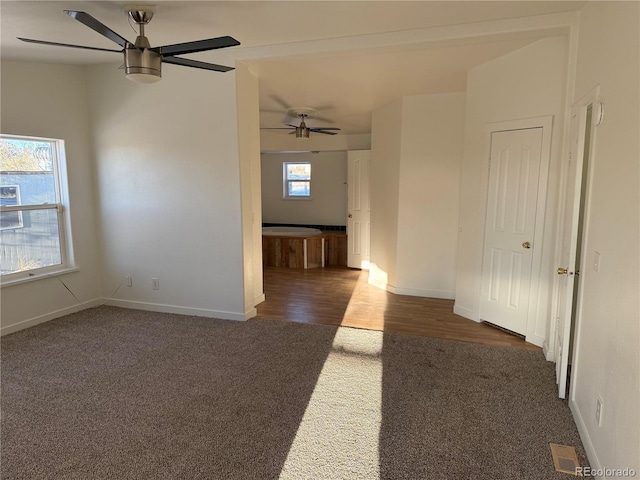 empty room with dark colored carpet and ceiling fan