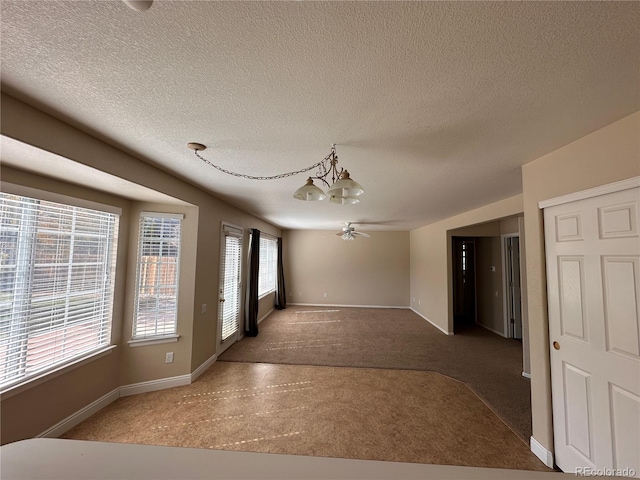 unfurnished room with a textured ceiling, ceiling fan with notable chandelier, and carpet floors