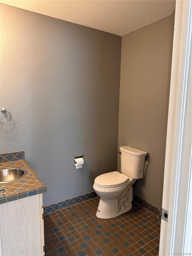 bathroom with vanity, a textured ceiling, toilet, and tile patterned floors