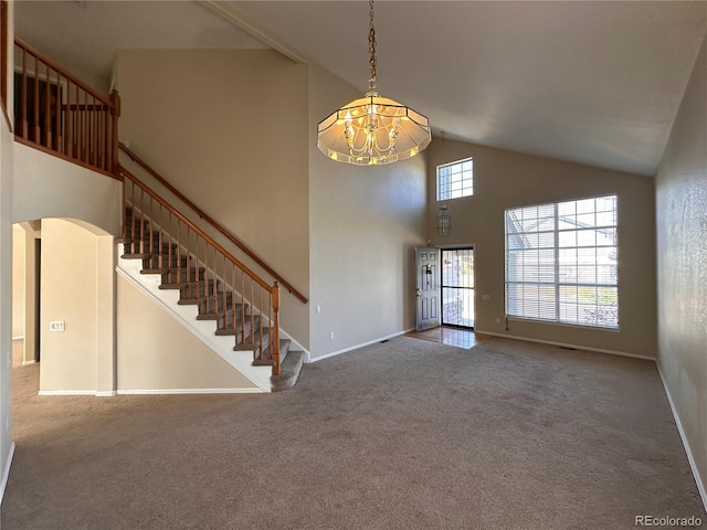 unfurnished living room with a chandelier, high vaulted ceiling, and carpet