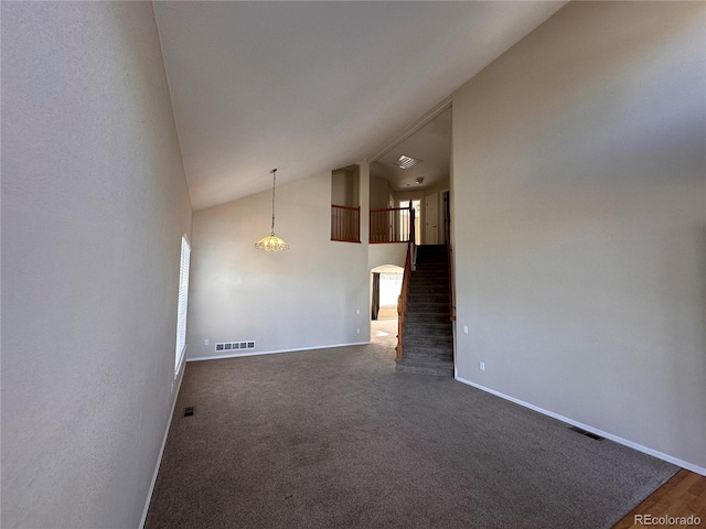 unfurnished living room featuring lofted ceiling and dark colored carpet