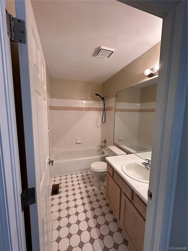 full bathroom featuring a textured ceiling, toilet, tile walls, shower / tub combination, and vanity