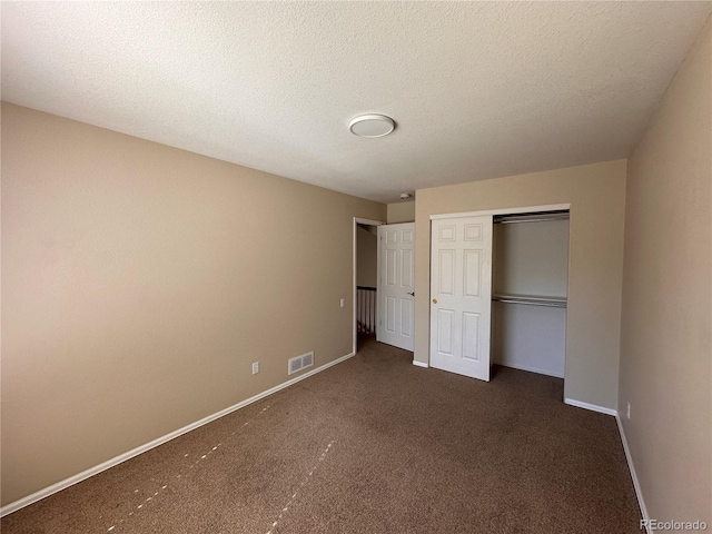 unfurnished bedroom featuring dark colored carpet, a textured ceiling, and a closet