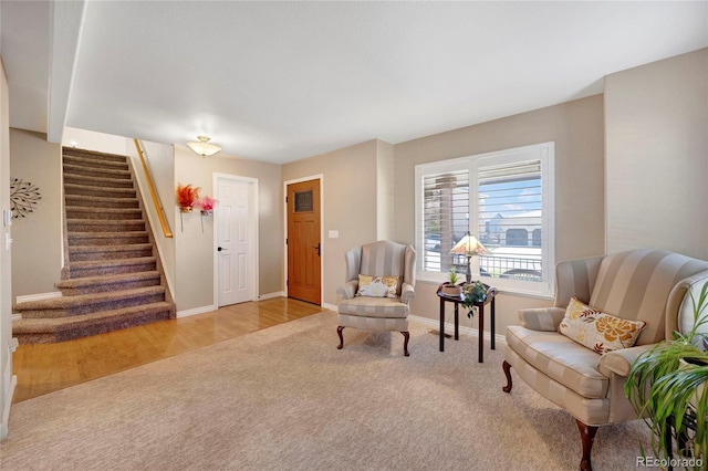 sitting room with carpet flooring, stairs, and baseboards