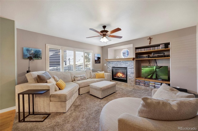 living room featuring a ceiling fan, a fireplace, and baseboards