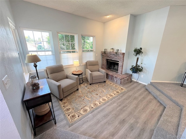 4760 S Wadsworth Blvd Unit F105, Littleton, CO 80123 - living area with wood finished floors, a textured ceiling, a fireplace, and baseboards