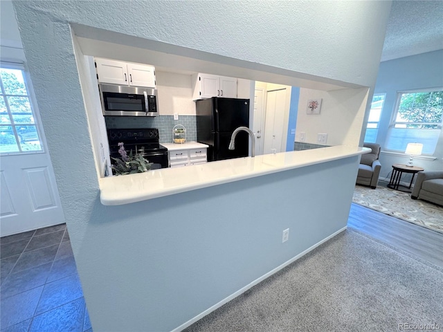 4760 S Wadsworth Blvd Unit F105, Littleton, CO 80123 - kitchen with black appliances, white cabinets, a textured ceiling, backsplash, and a peninsula
