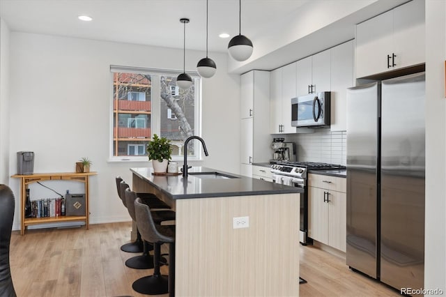 3101 W 47th Ave Unit 14, Denver, CO 80211 - kitchen featuring appliances with stainless steel finishes, dark countertops, light wood-style floors, a breakfast bar, and recessed lighting