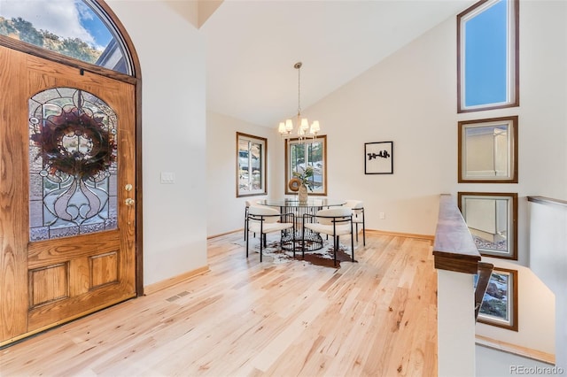 foyer entrance featuring high vaulted ceiling, light hardwood / wood-style floors, and a notable chandelier