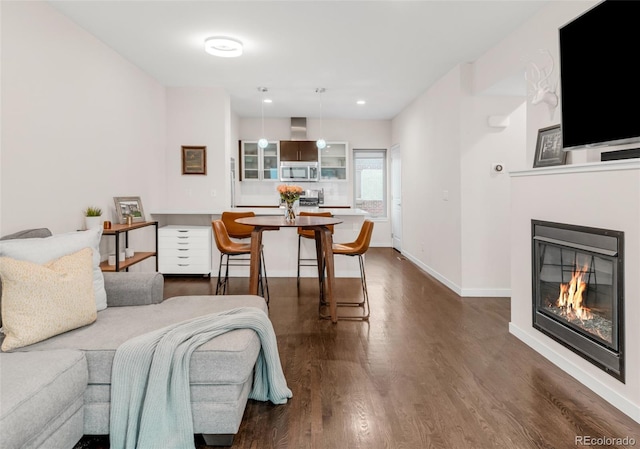 bedroom with dark wood-type flooring, recessed lighting, a glass covered fireplace, and baseboards