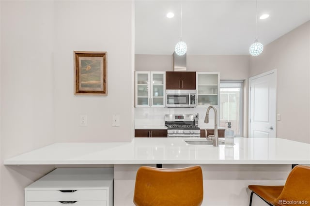 kitchen featuring light countertops, appliances with stainless steel finishes, a kitchen bar, and a sink