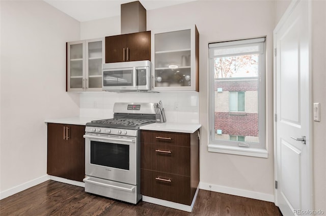 kitchen featuring dark wood-style floors, stainless steel appliances, light countertops, and glass insert cabinets