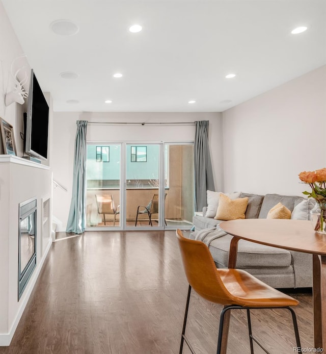 living area featuring a glass covered fireplace, recessed lighting, and wood finished floors