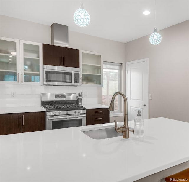 kitchen featuring stainless steel appliances, light countertops, hanging light fixtures, a sink, and dark brown cabinetry