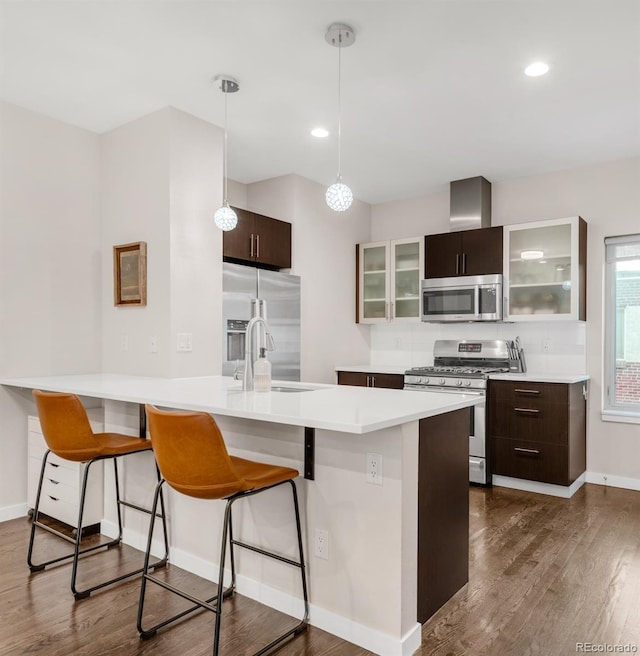 kitchen featuring stainless steel appliances, a breakfast bar, dark wood-type flooring, and a sink