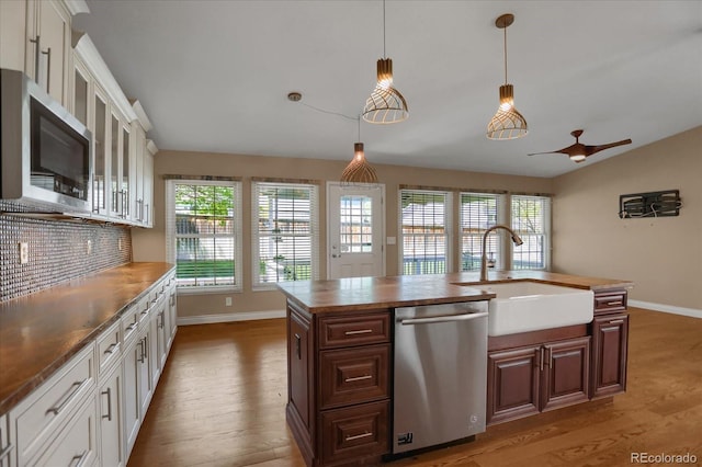 8951 Greenwich St, Highlands Ranch, CO 80130 - kitchen with appliances with stainless steel finishes, a sink, light wood finished floors, baseboards, and decorative backsplash