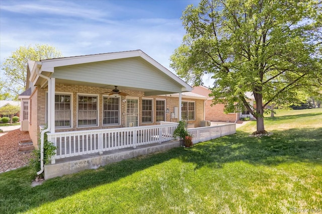 8951 Greenwich St, Highlands Ranch, CO 80130 - back of property featuring a ceiling fan, a lawn, brick siding, and covered porch
