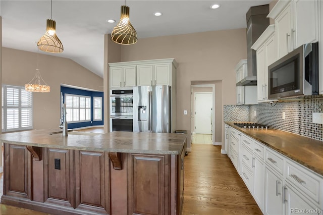 8951 Greenwich St, Highlands Ranch, CO 80130 - kitchen featuring appliances with stainless steel finishes, a spacious island, tasteful backsplash, vaulted ceiling, and recessed lighting