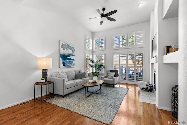 9491 Southern Hills Cir, Lone Tree, CO 80124 - living room featuring a ceiling fan, hardwood / wood-style floors, a fireplace, and a towering ceiling