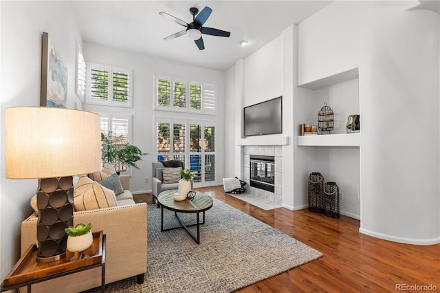 9491 Southern Hills Cir, Lone Tree, CO 80124 - living room featuring a ceiling fan, a tile fireplace, wood finished floors, and a high ceiling