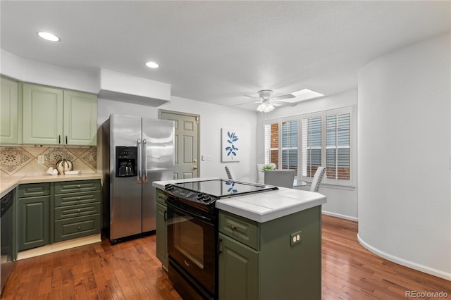 9491 Southern Hills Cir, Lone Tree, CO 80124 - kitchen with green cabinetry, stainless steel fridge, black range with electric stovetop, hardwood / wood-style floors, and recessed lighting