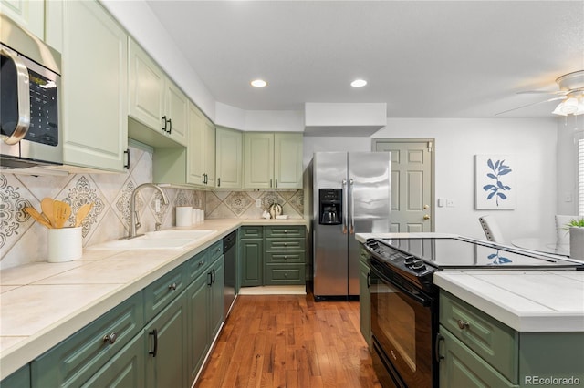 9491 Southern Hills Cir, Lone Tree, CO 80124 - kitchen featuring green cabinets, appliances with stainless steel finishes, light countertops, wood finished floors, and backsplash