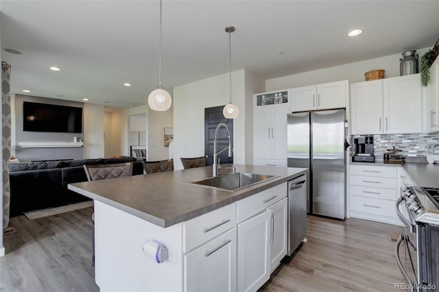 10906 Touchstone Loop, Parker, CO 80134 - kitchen with appliances with stainless steel finishes, white cabinetry, hanging light fixtures, light wood-style flooring, and an island with sink
