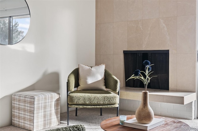 sitting room featuring a tiled fireplace and carpet