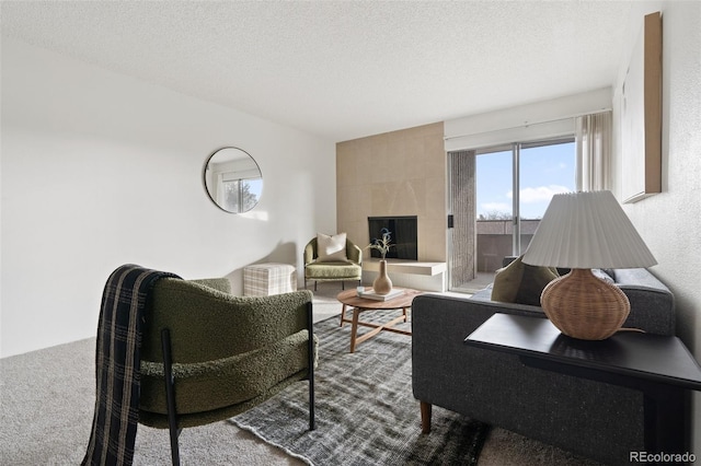 carpeted living room with a tiled fireplace and a textured ceiling