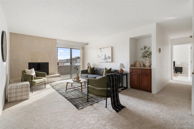 carpeted living room with a tiled fireplace and a textured ceiling