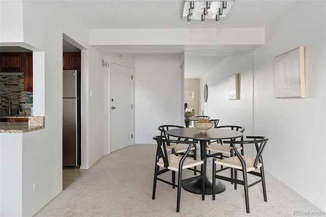 carpeted dining area with sink and a textured ceiling