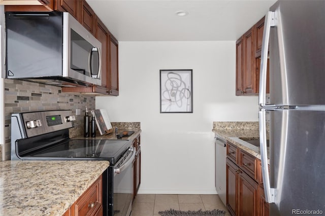 kitchen with tasteful backsplash, stainless steel appliances, light stone countertops, and light tile patterned floors