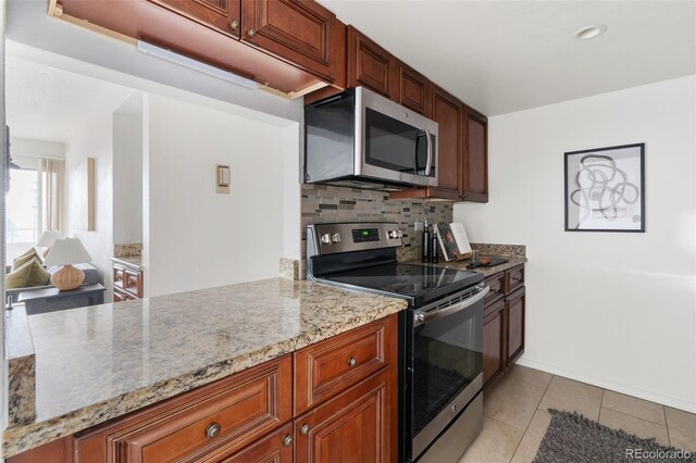 kitchen with tasteful backsplash, stainless steel appliances, light stone countertops, and light tile patterned floors