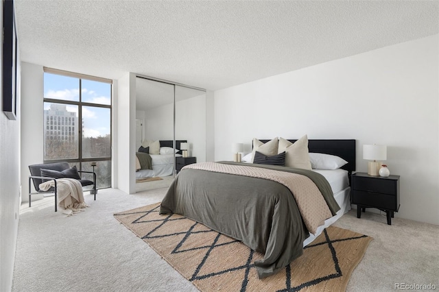 carpeted bedroom with a closet, floor to ceiling windows, and a textured ceiling