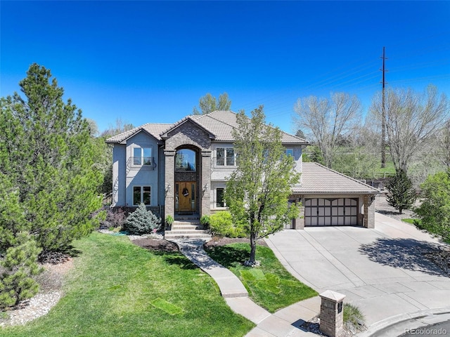 french country home featuring an attached garage, a tiled roof, a front lawn, and driveway