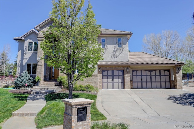 view of front of property featuring a tile roof, stucco siding, brick siding, and driveway
