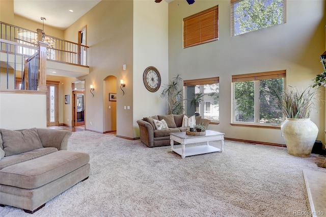 living room featuring a high ceiling, carpet floors, arched walkways, and baseboards