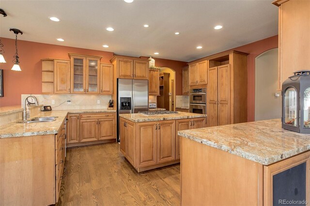 kitchen with a sink, open shelves, light wood finished floors, arched walkways, and appliances with stainless steel finishes