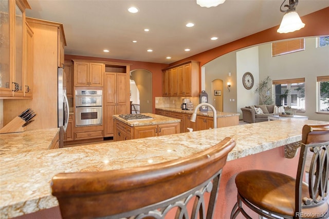kitchen with a peninsula, a sink, arched walkways, appliances with stainless steel finishes, and recessed lighting