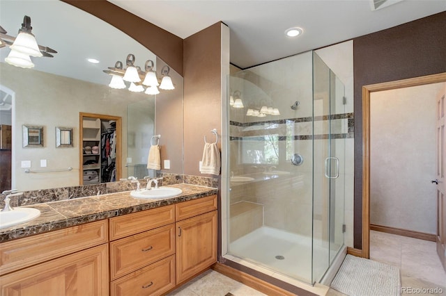 bathroom with a shower stall, tile patterned floors, a sink, and a walk in closet