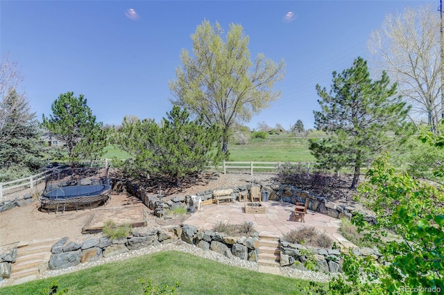 view of yard with a fire pit, a trampoline, a patio area, and fence