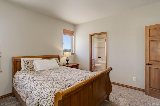 bedroom with ensuite bath, light colored carpet, and baseboards