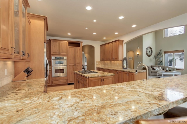 12825 W 81st Ave, Arvada, CO 80005 - kitchen with arched walkways, light stone countertops, a peninsula, recessed lighting, and appliances with stainless steel finishes