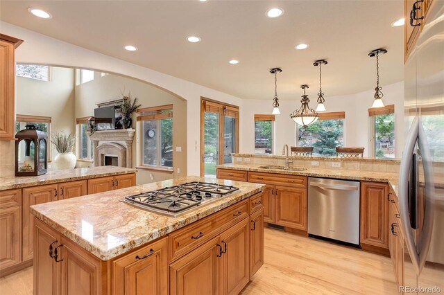12825 W 81st Ave, Arvada, CO 80005 - kitchen with stainless steel appliances, a sink, a kitchen island, recessed lighting, and light wood-style floors