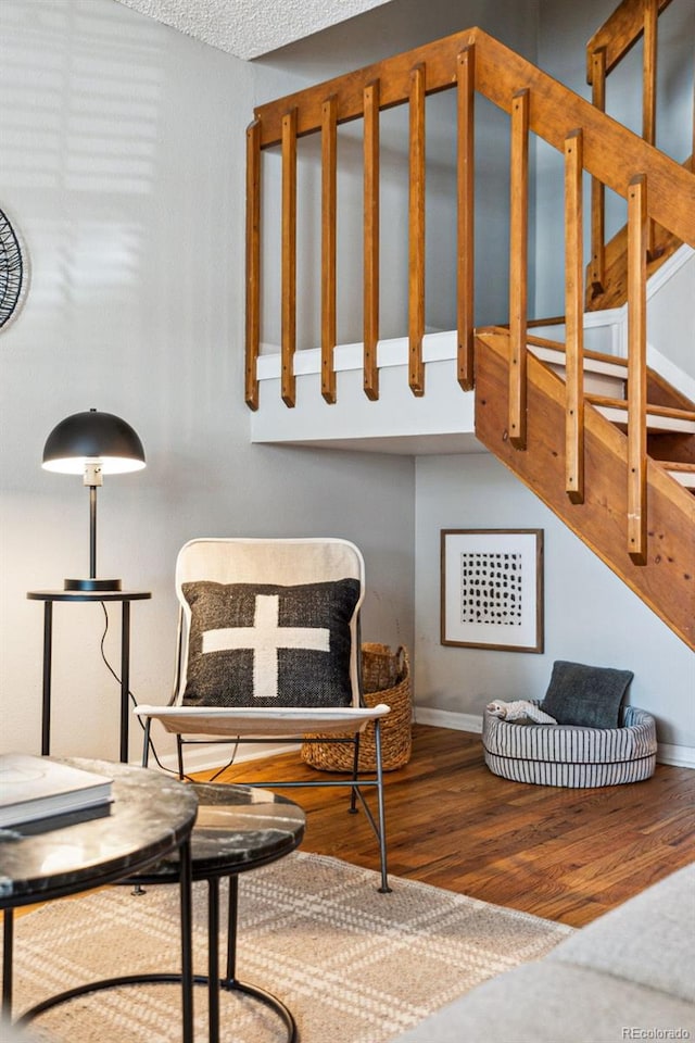 living area with stairway, wood finished floors, and baseboards