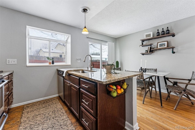 kitchen with a peninsula, light stone countertops, hanging light fixtures, a textured ceiling, and light wood-style floors