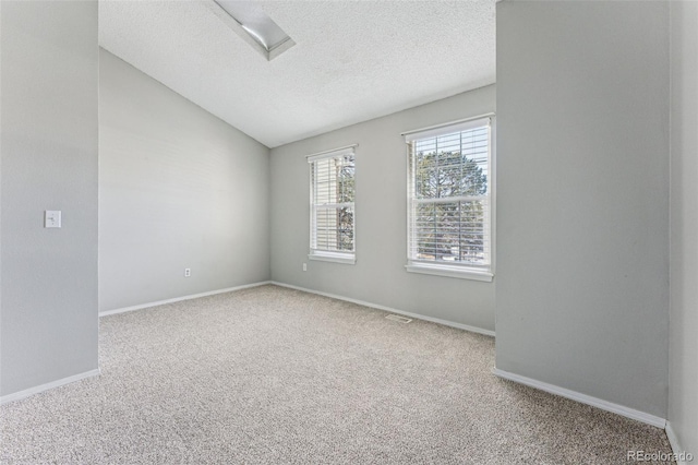 carpeted spare room with lofted ceiling, a textured ceiling, and baseboards