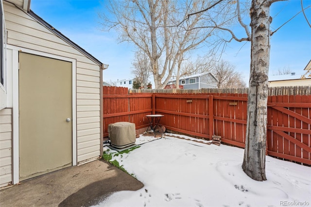 snow covered patio featuring a storage unit, fence, and an outdoor structure