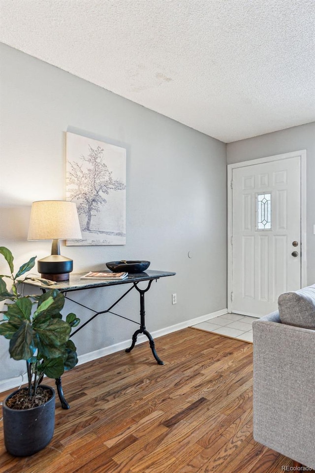 entryway featuring a textured ceiling, wood finished floors, and baseboards